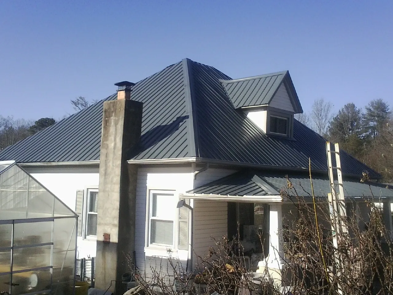 Dark blue standing seam metal roof on a white farmhouse with dormer — Slate & Tile Roof Repair by Roofing Brothers in Bally