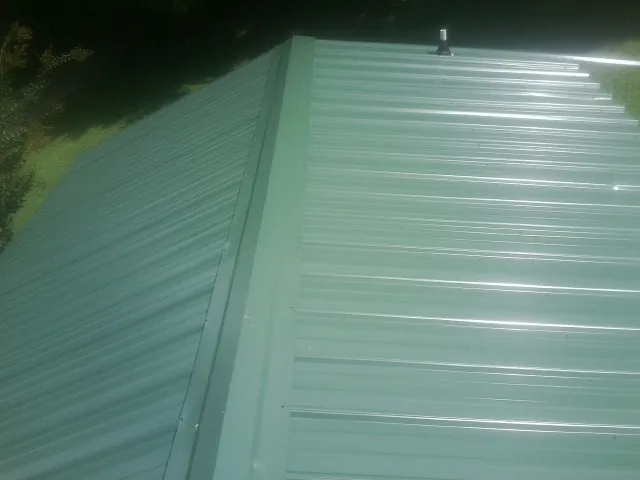 New green metal panels meeting at the ridge of a roof — Flat Roof Repair work by our crew in Bally