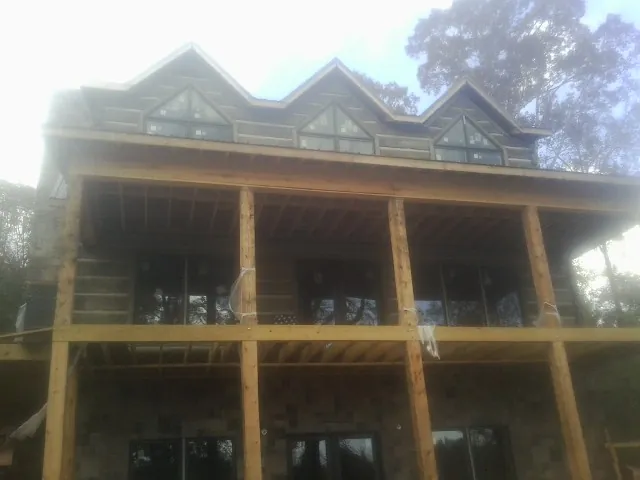 Dormers and porch framing on a large log home under construction — Roof Coating work by our crew in Bally