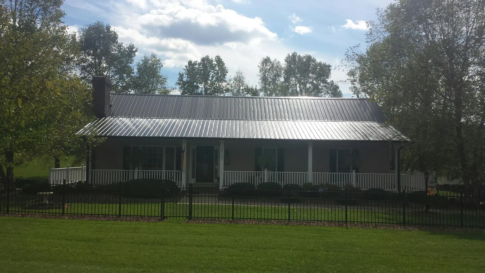 Gray metal roof on a brick ranch with a full width front porch — Gutter Guard Installation work by our crew in Bally