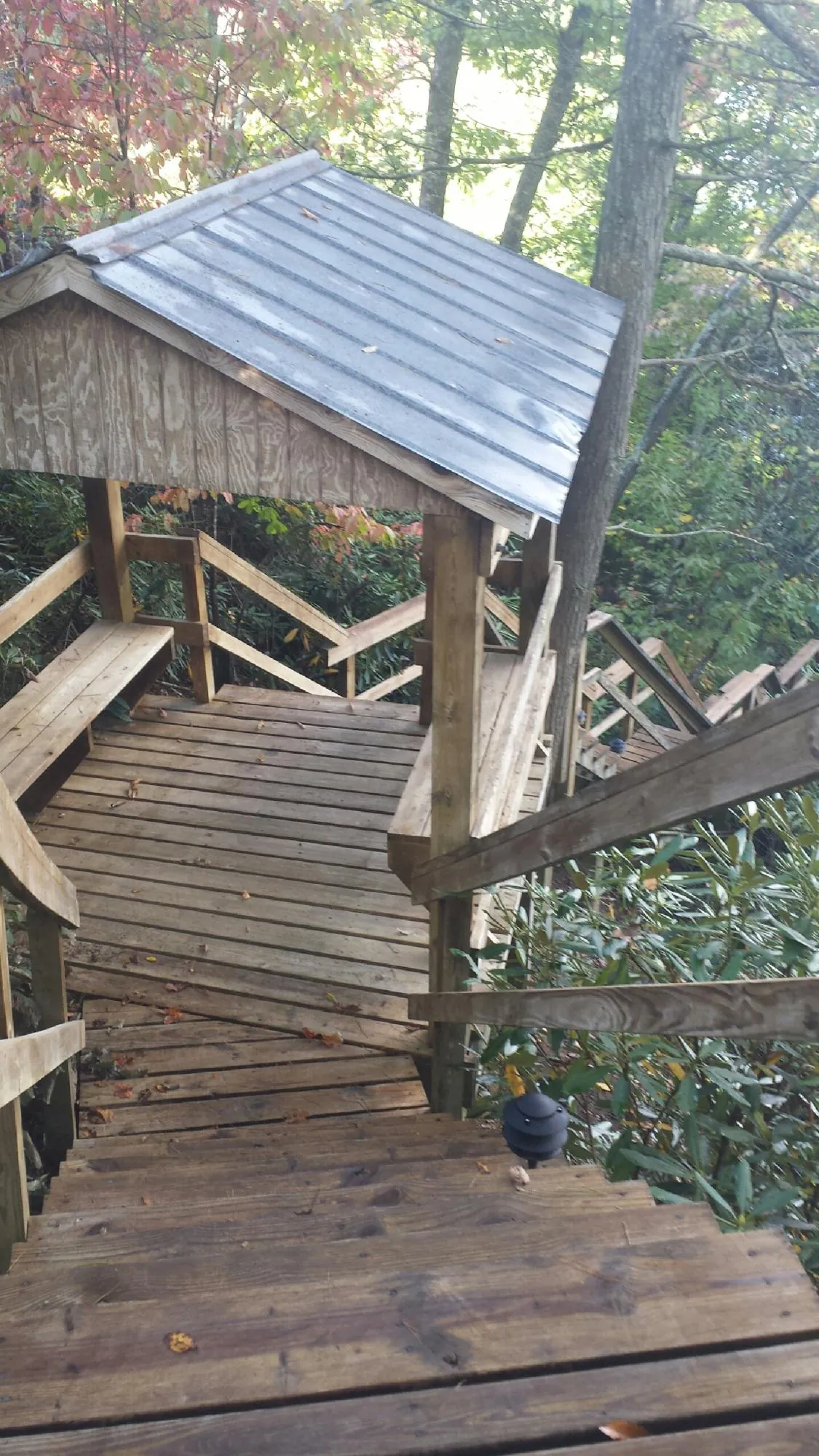Metal roofed shelter over wooden steps on a wooded walkway — Skylight Repair & Installation work by our crew in Bally