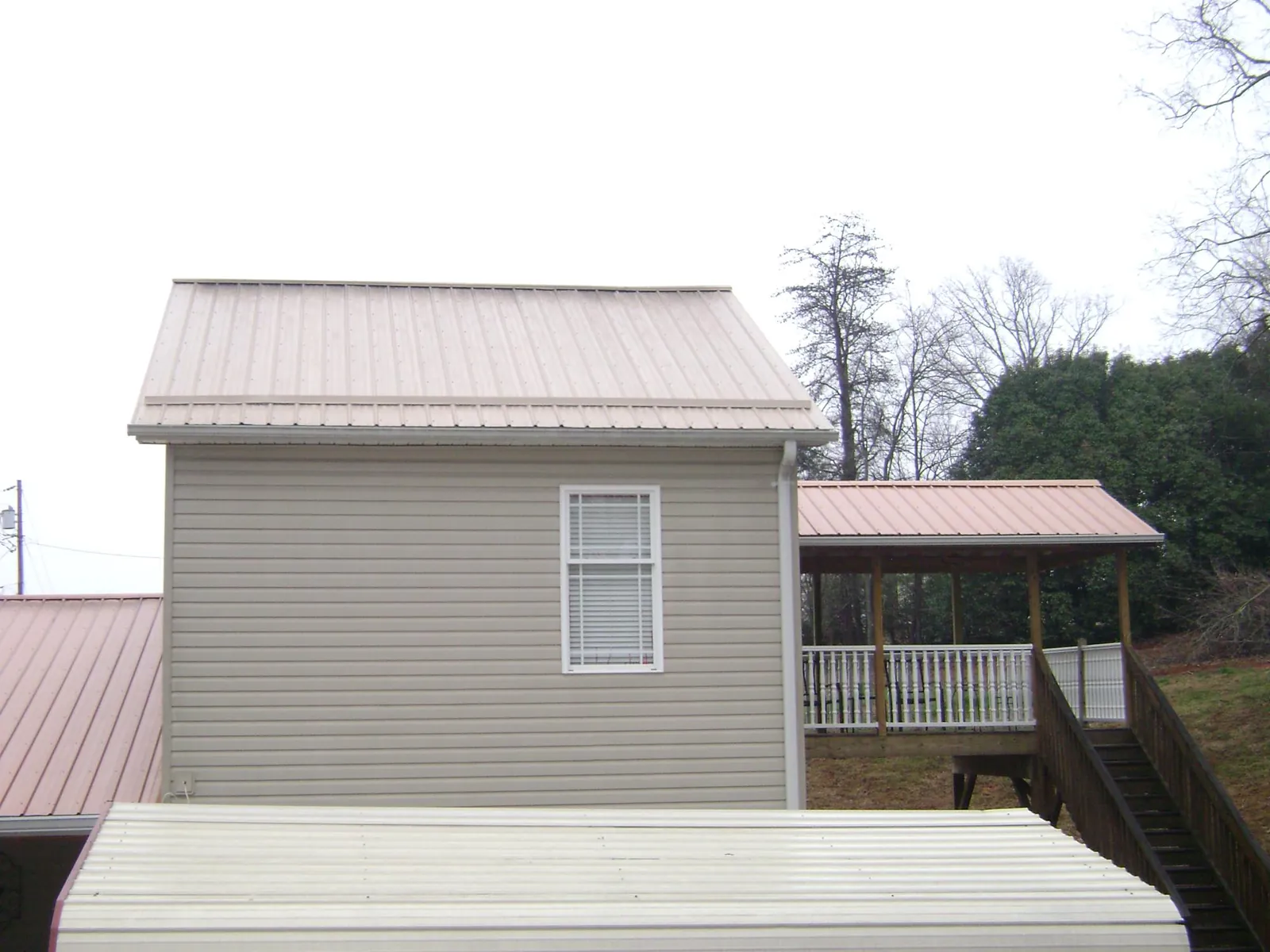 Tan metal roofs on a two story addition and attached porch, from a Roof Replacement job in Bally