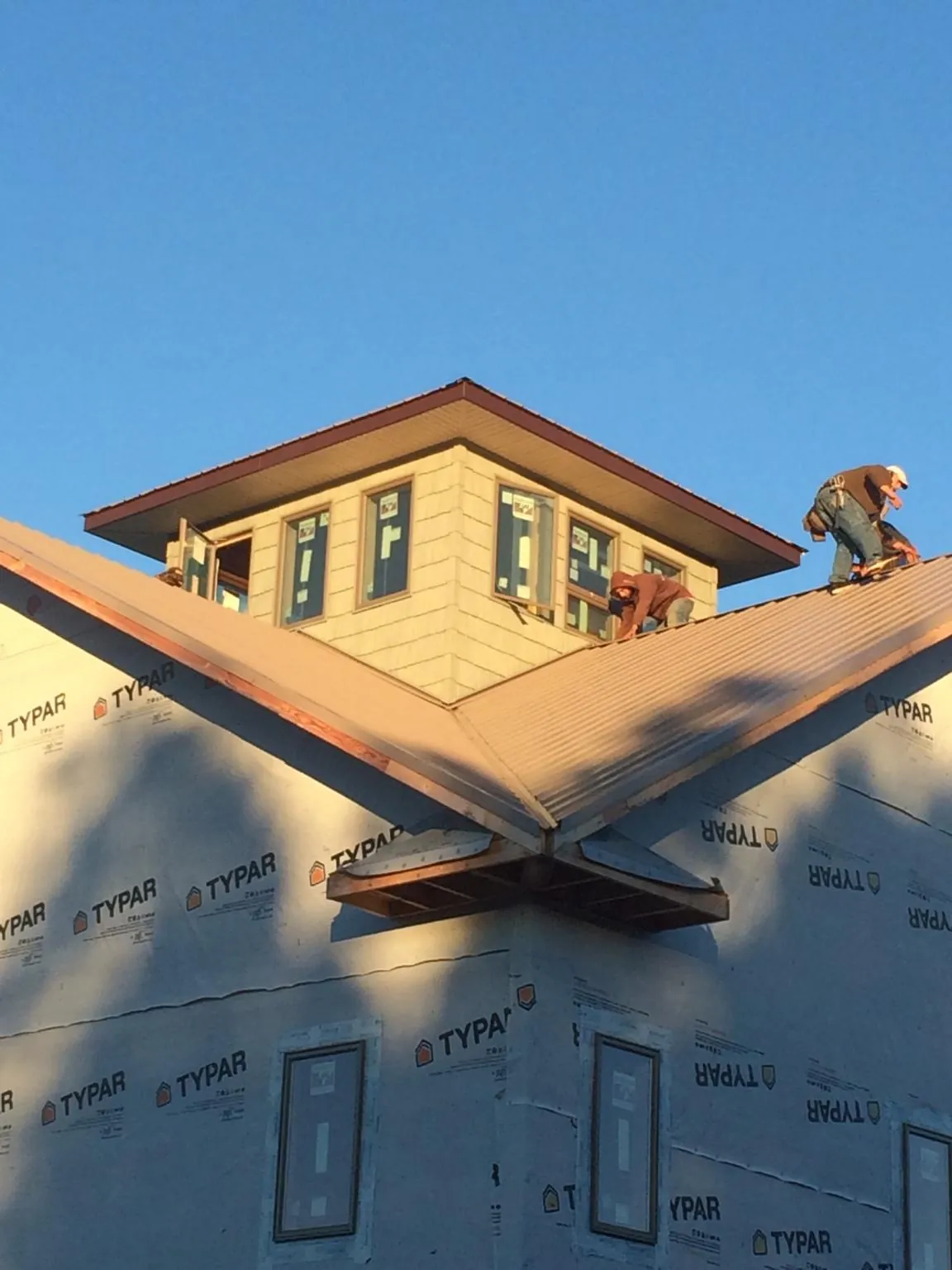 Roofers working around a rooftop cupola on a new metal roof at sunset — Roof Waterproofing in Bally by Roofing Brothers